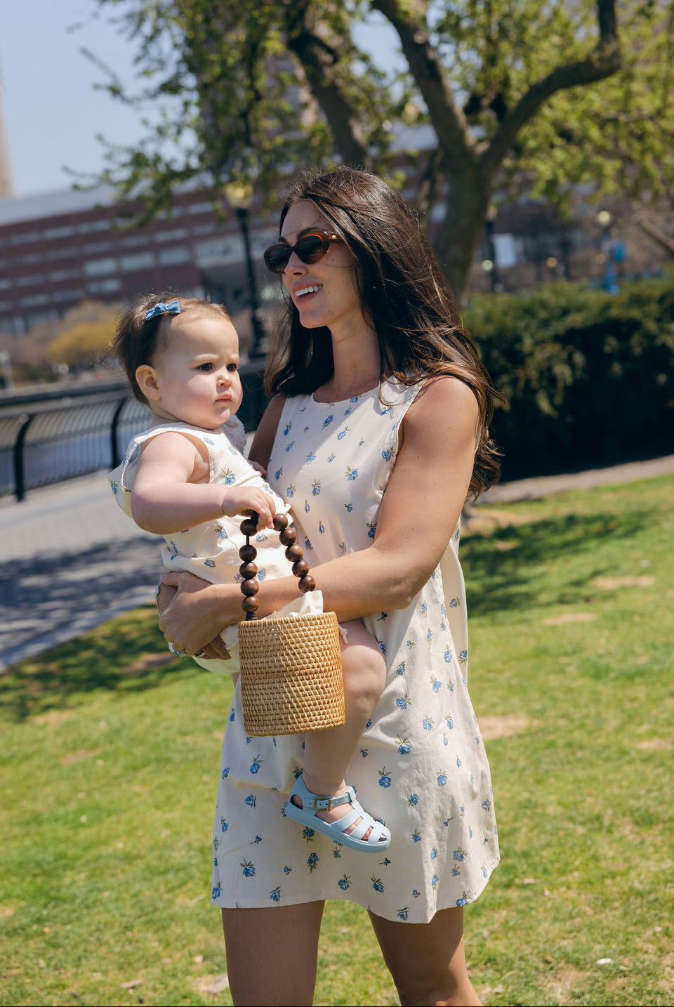 Blue Posey Mini Gili and Little Gili Mommy and Me matching floral dresses, mom holding baby spring summer 2026 Puka The Label