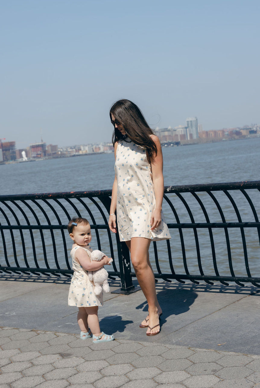 Blue Posey Mini Gili Mommy and Me matching floral dresses at waterfront, mother daughter spring summer 2026 coordinating blue dress Puka The Label