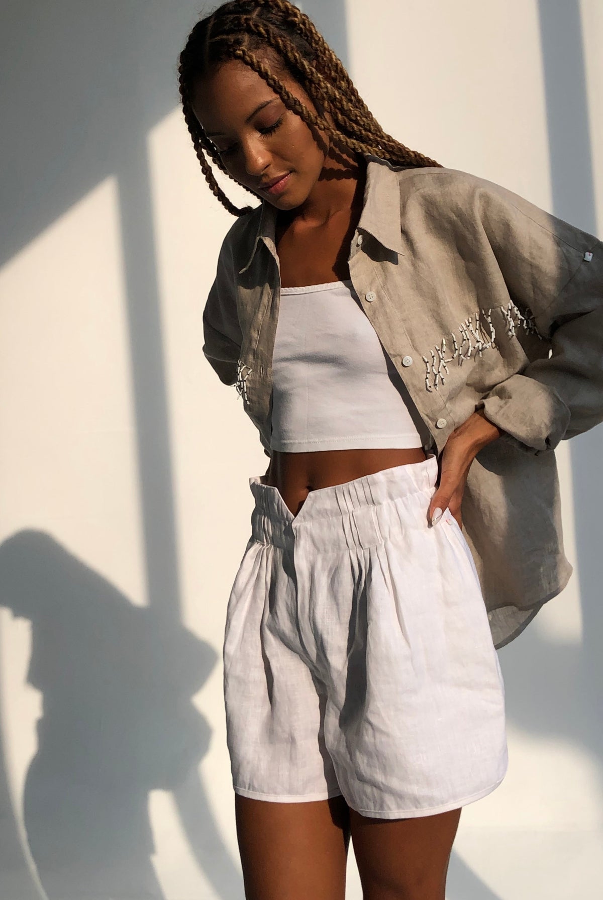 Women's white linen shorts outfit — Puka Pantai Short styled with fringe top, easy summer look for vacation and coastal weekends
