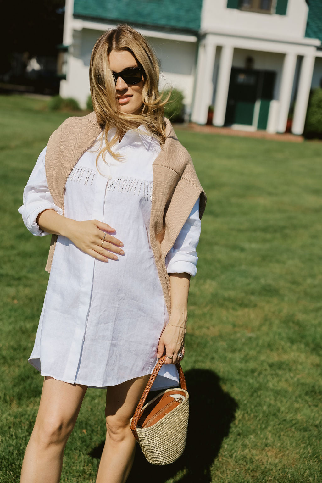 White linen hand-beaded fringe Ulu Dress with camel cardigan draped over shoulders at Montauk Yacht Club, East Hampton Hamptons summer outfit 2026