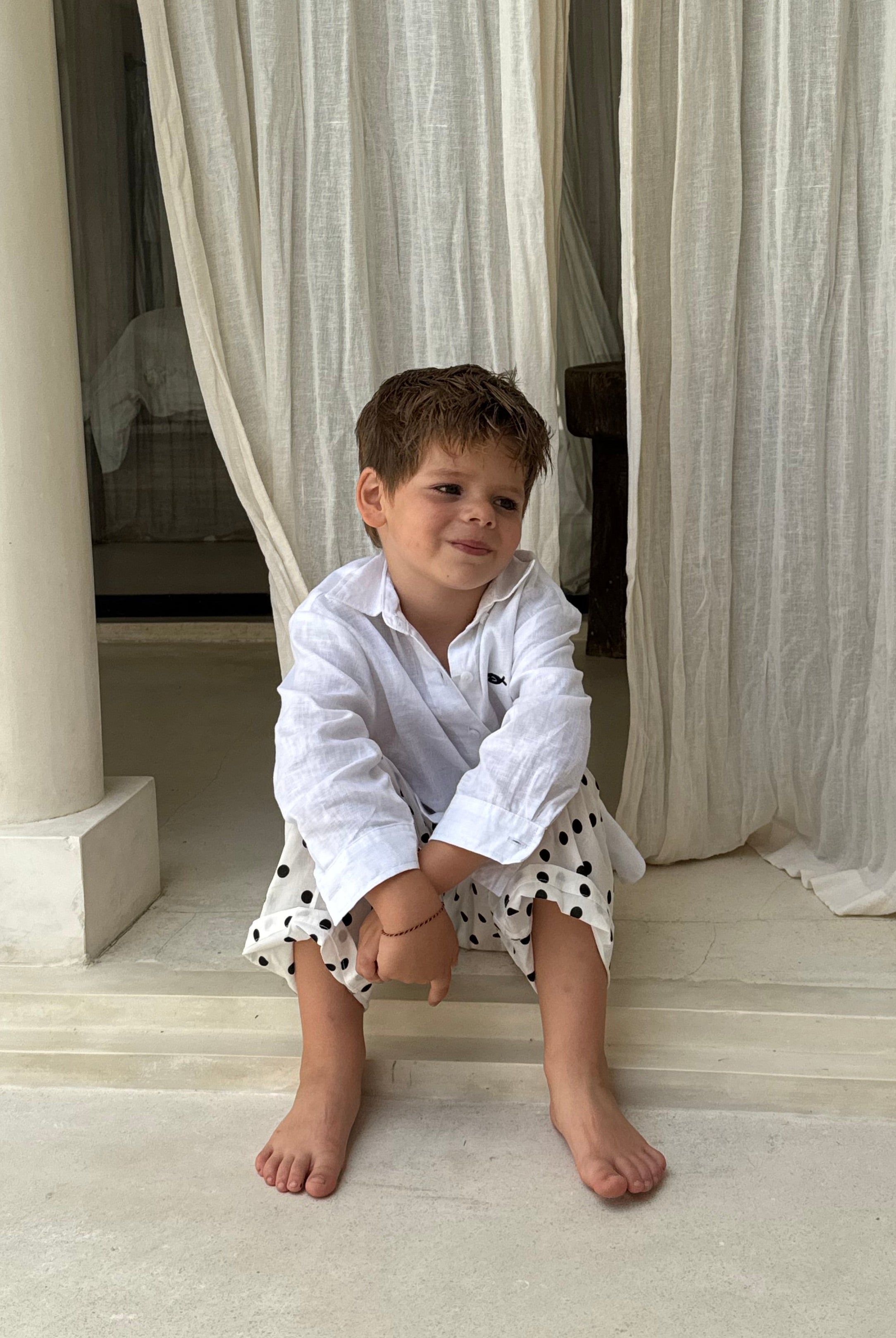Young boy in Pantai Polka Dot Pants on villa steps in Bali, playful kids beach pants perfect for Mommy and Me matching