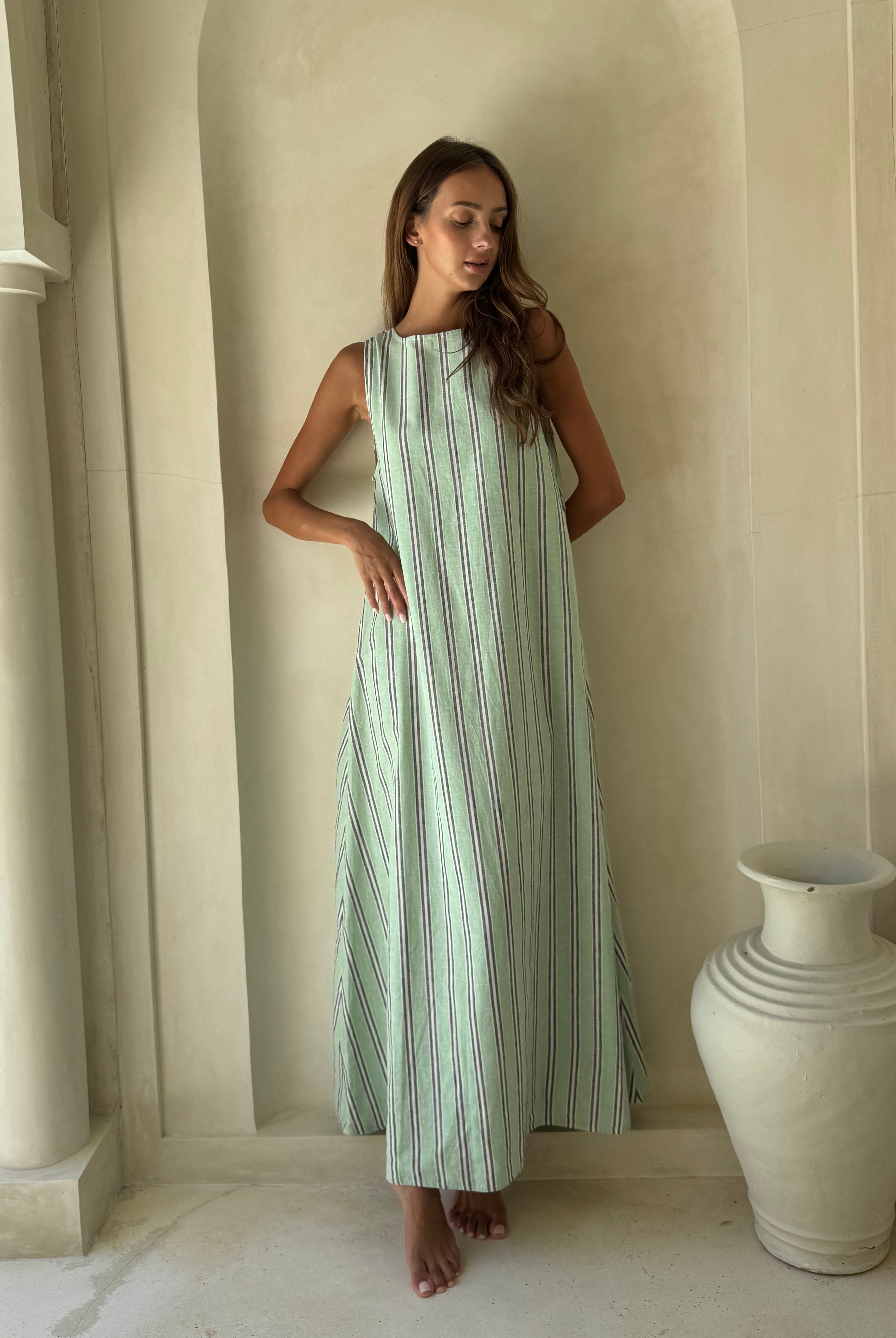 Woman in green, navy and white Gili Stripe Maxi Dress for a Laguna Beach afternoon, breezy floor-length beach style