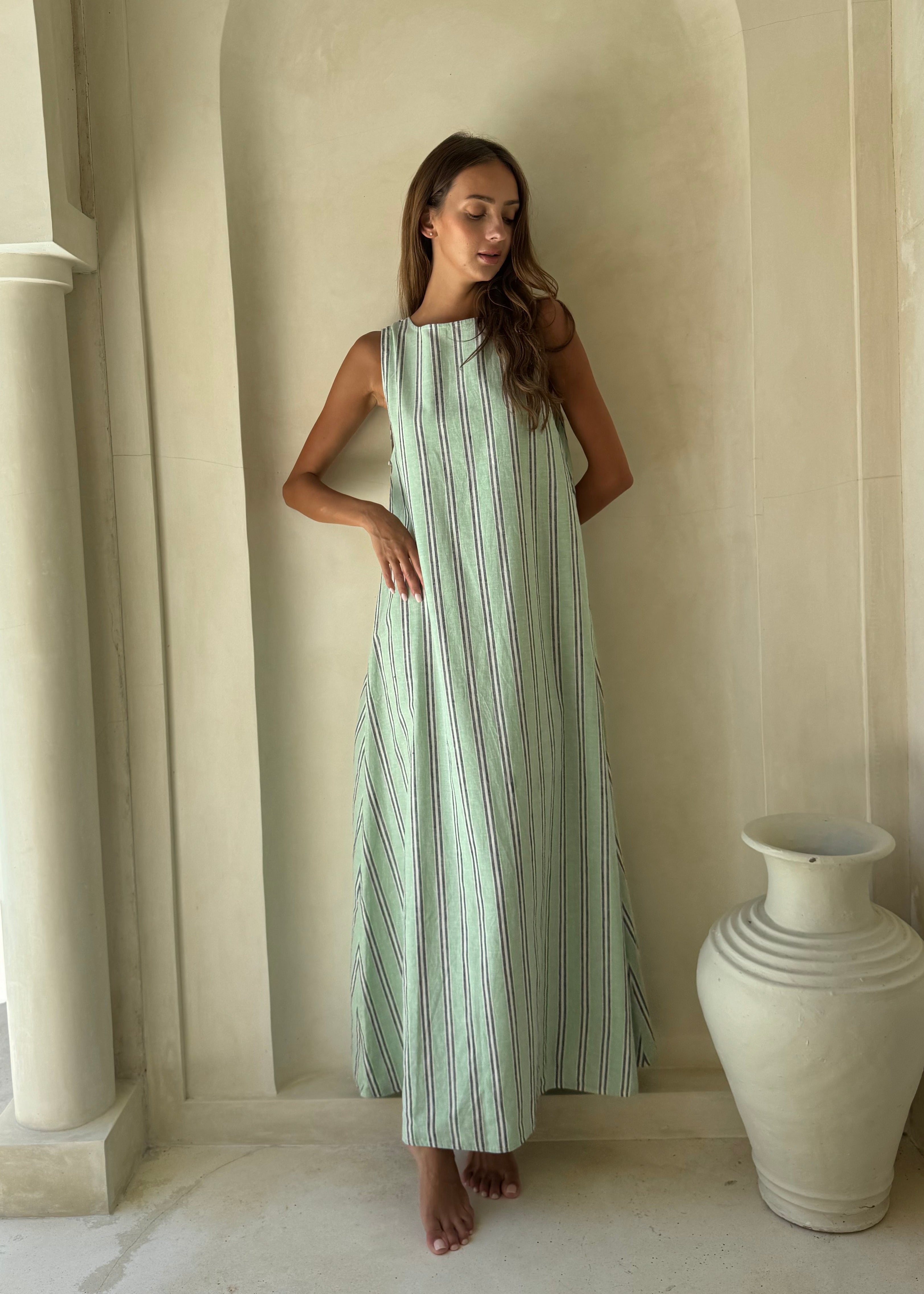 Woman in green, navy and white Gili Stripe Maxi Dress for a Laguna Beach afternoon, breezy floor-length beach style
