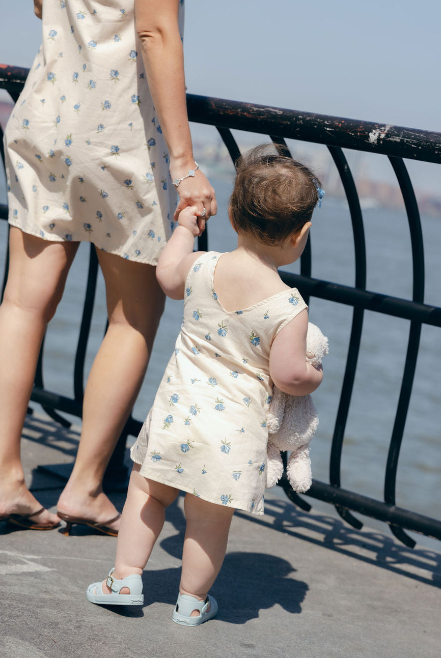 Blue Posey Little Gili girls cotton dress from behind, mother daughter holding hands at waterfront in matching spring dresses Puka The Label