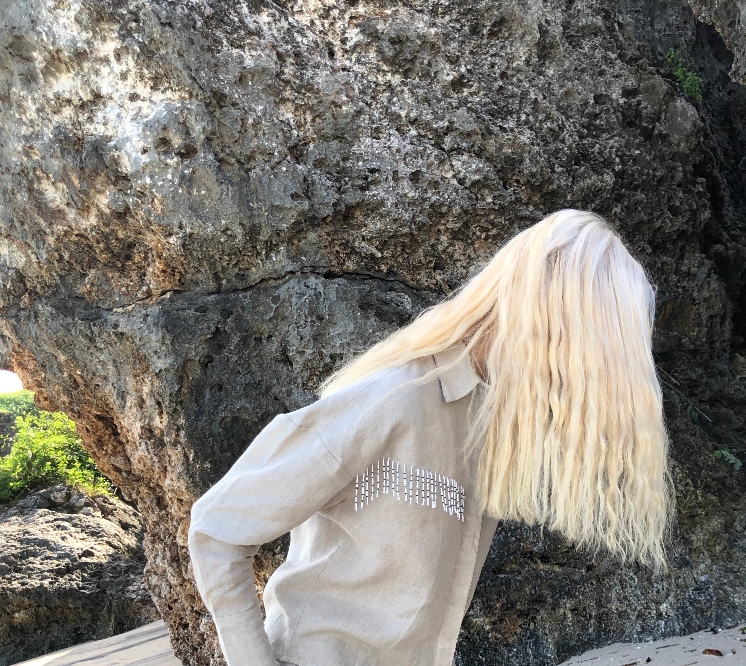 Sand linen shorts and button-up Ulu top styled as a complete neutral coastal beach outfit for women. Beach set in neutral linen that has a western spin (beaded fringe)