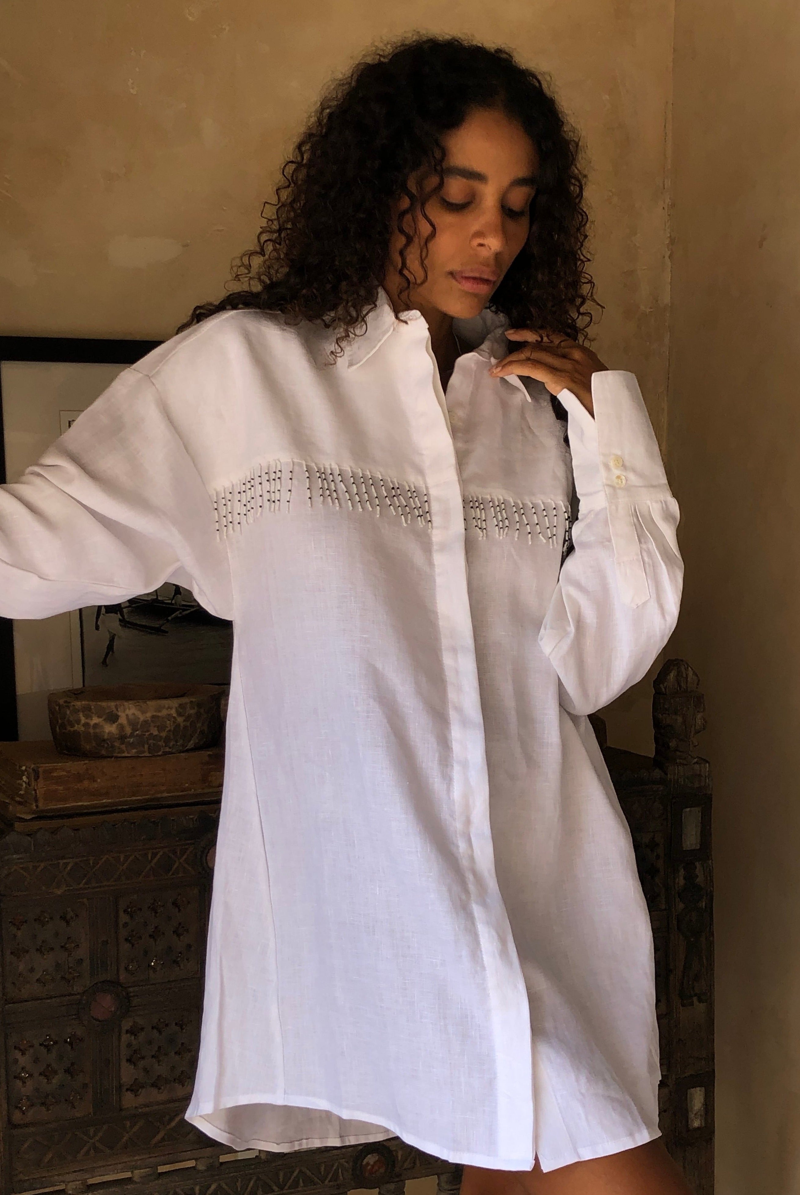 White linen button-up dress worn as chic beach cover-up with hand-beaded fringe 2026, unique artisan linen dress for pool day and resort vacation