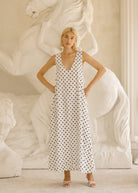 Woman in a polka dot dress standing in front of a decorative wall. Chic black and white polkadot dress