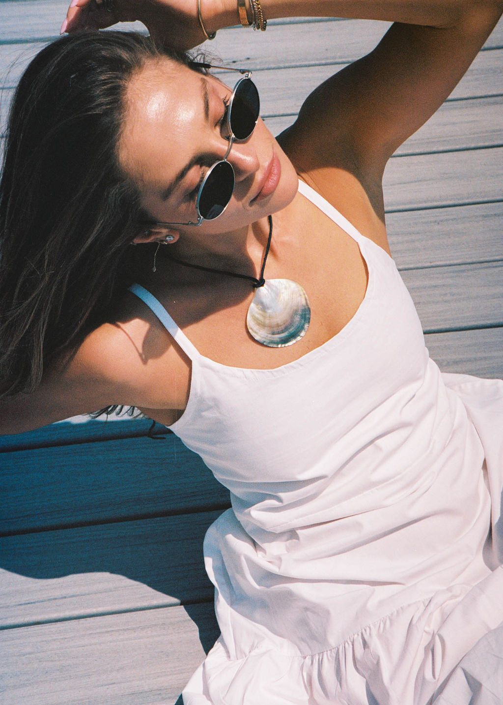 Woman in a white dress with sunglasses on a wooden deck in the Hamptons