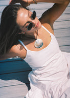 Woman in a white dress with sunglasses on a wooden deck in the Hamptons
