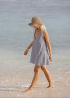 Woman in black gingham mini dress with a v-neck and high neck and a lack of color beach hat