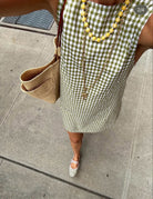 Claire O'Callaghan (@everydayoc) in our mini green gingham dress — paired with a raffia tote, layered necklaces, and striped mary jane flats.