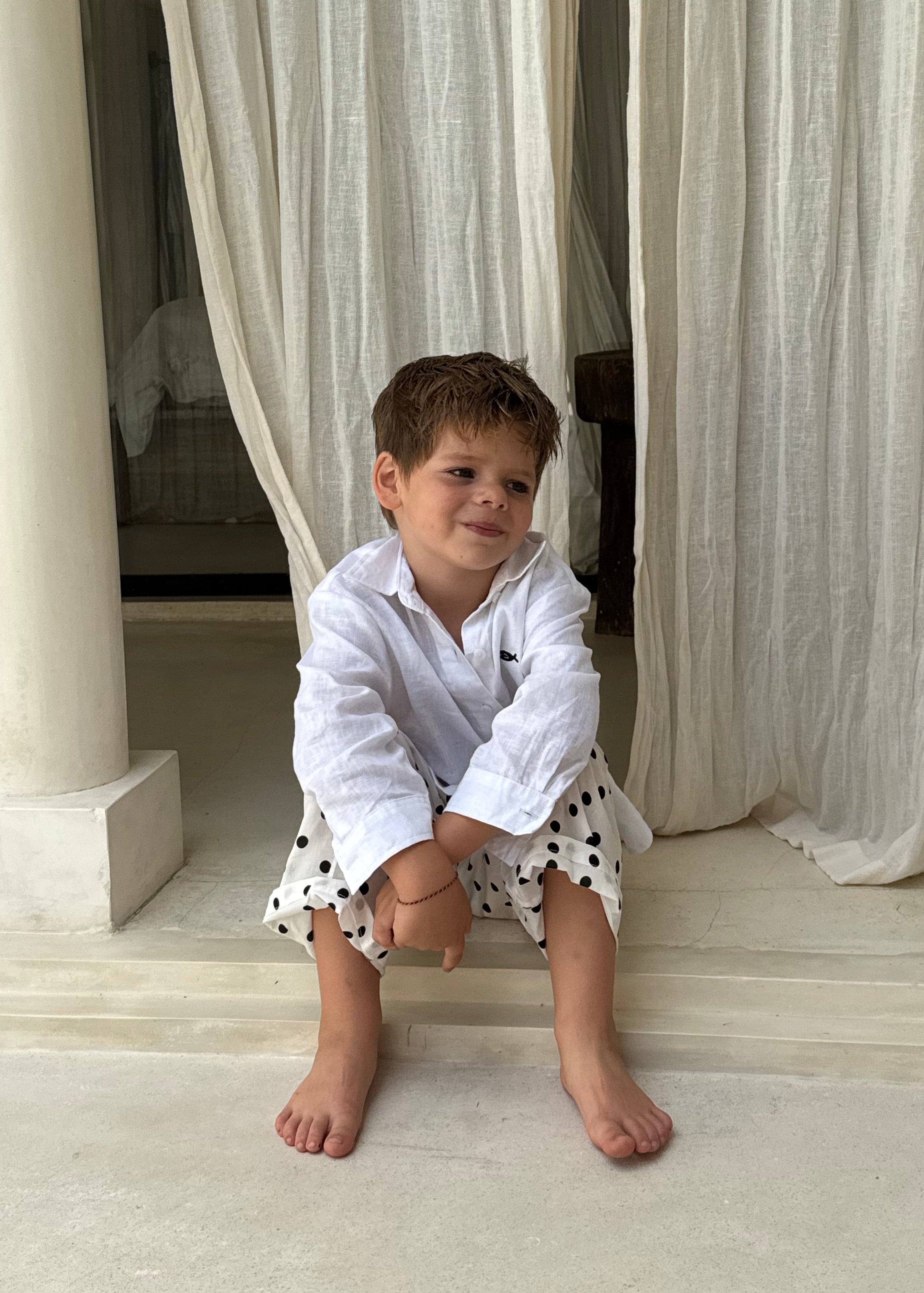 Young boy in Pantai Polka Dot Pants on villa steps in Bali, playful kids beach pants perfect for Mommy and Me matching
