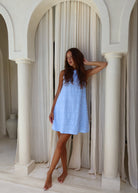 Couper x Puka Exclusive Mini Gili light blue feathered cotton mini dress Mediterranean archway resort getaway, effortless vacation summer mini dress 2026 Puka The Label