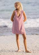 Woman in a red and white checkered dress standing on a beach.