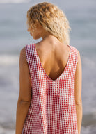 Woman wearing a red and white checkered dress standing by the ocean.