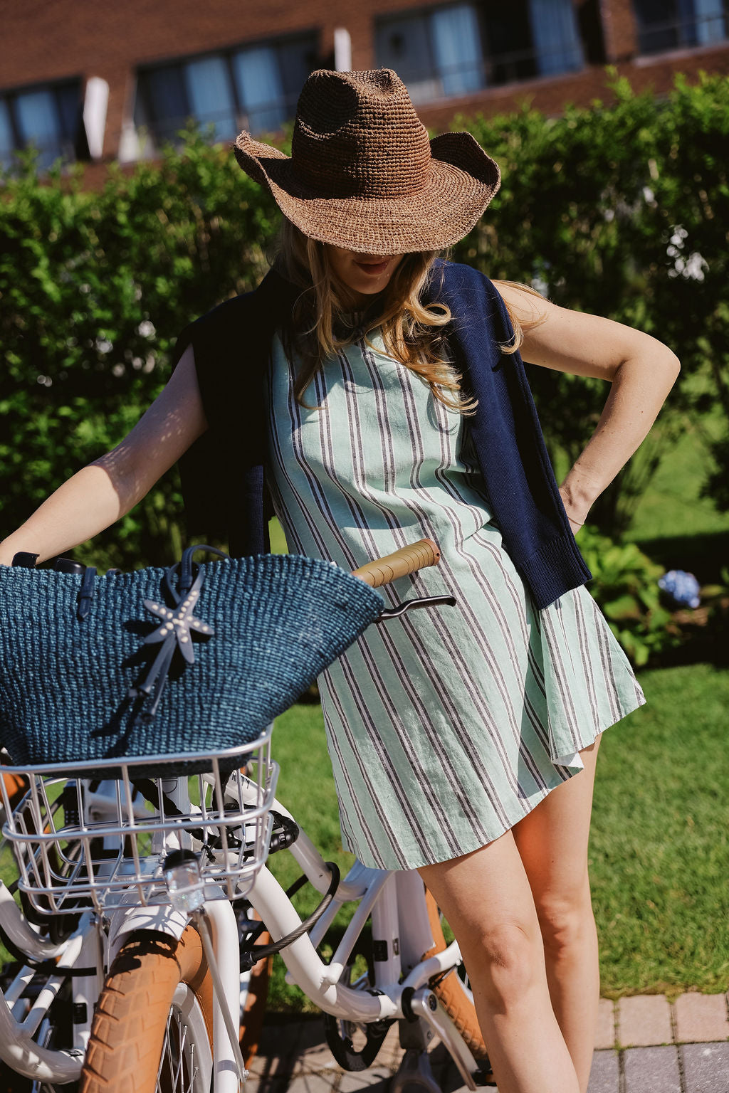 Green stripe Mini Gili dress styled with raffia cowboy hat and navy starfish tote bag next to Montauk Yacht Club beach bikes, MTK preppy summer outfit 2026