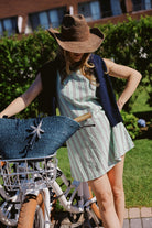 Green stripe Mini Gili dress styled with raffia cowboy hat and navy starfish tote bag next to Montauk Yacht Club beach bikes, MTK preppy summer outfit 2026