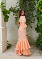 Peach ruffle dress spring garden party outfit idea, woman in soft peach cotton maxi surrounded by tropical greenery