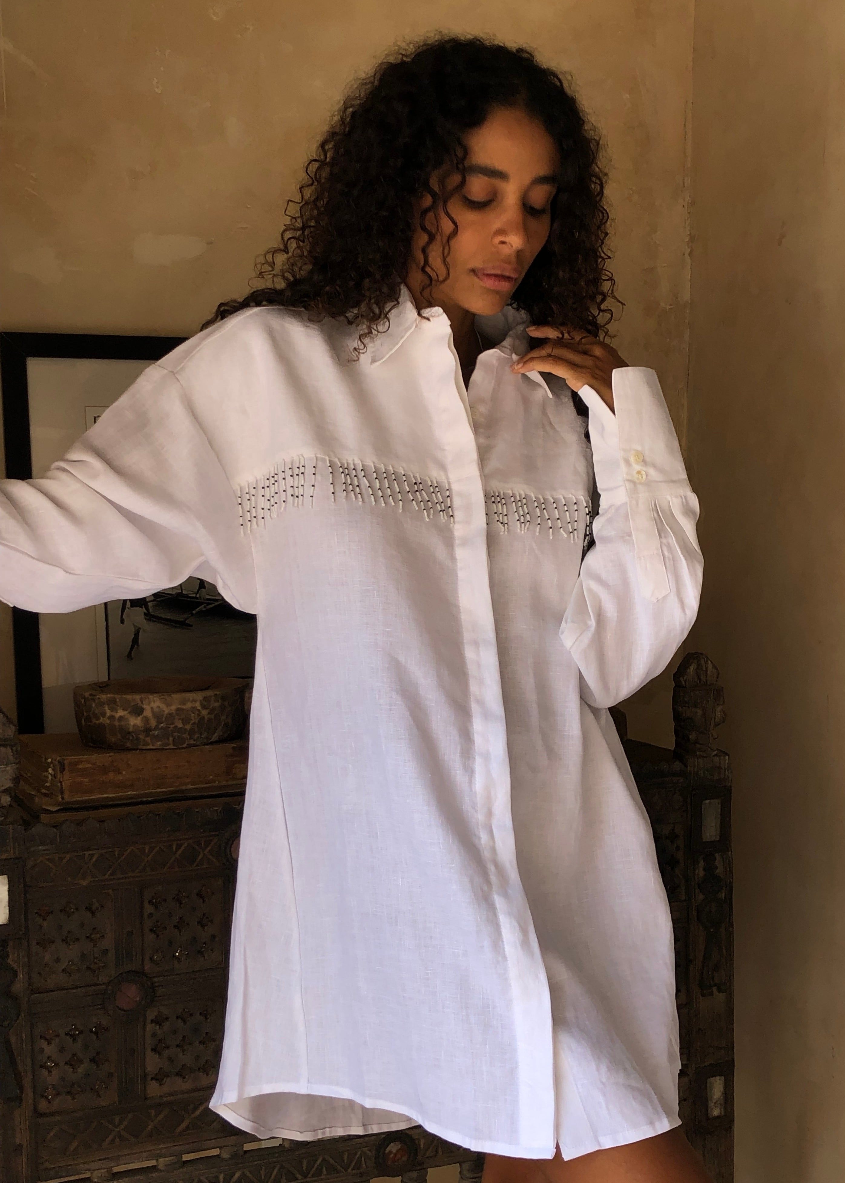 White linen button-up dress worn as chic beach cover-up with hand-beaded fringe 2026, unique artisan linen dress for pool day and resort vacation
